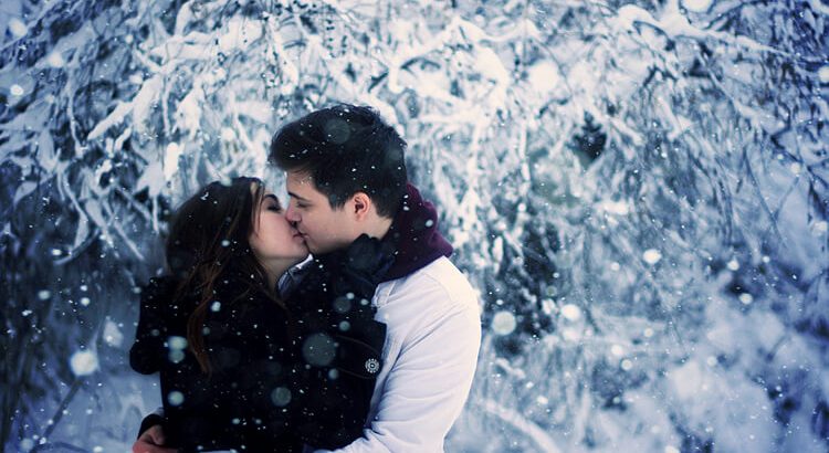 couple are kissing under the snow