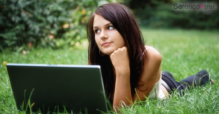 woman with laptop lying on a grass
